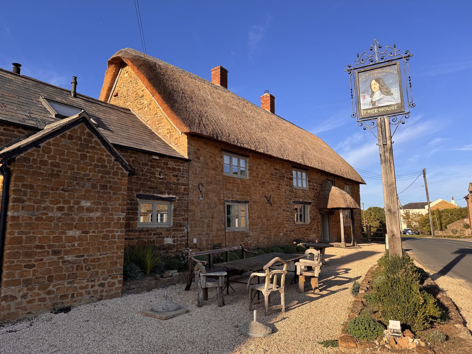 The thatched stone exterior and hanging pub sign of the Duke of Cumberland's Head in Clifton, Oxfordshire